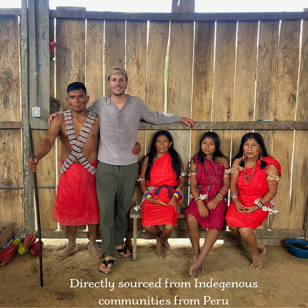 Man posing with four women in traditional attire against a wooden fence.