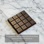 Willie's Cacao 71% Sambirano Gold Madagascar Dark Chocolate bar unwrapped on cacao beans with lively summer fruit notes
