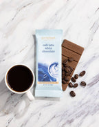 Cafe Latte White Chocolate bar with coffee beans and a cup of coffee on a marble surface
