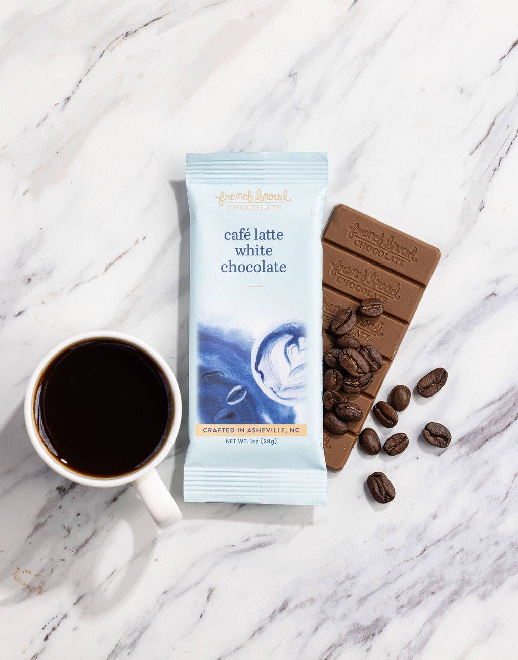 Cafe Latte White Chocolate bar with coffee beans and a cup of coffee on a marble surface