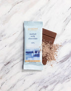 French Broad Chocolate 45% Malted Milk Chocolate bar and packaging on marble surface, crafted in Asheville NC, 1oz 28g