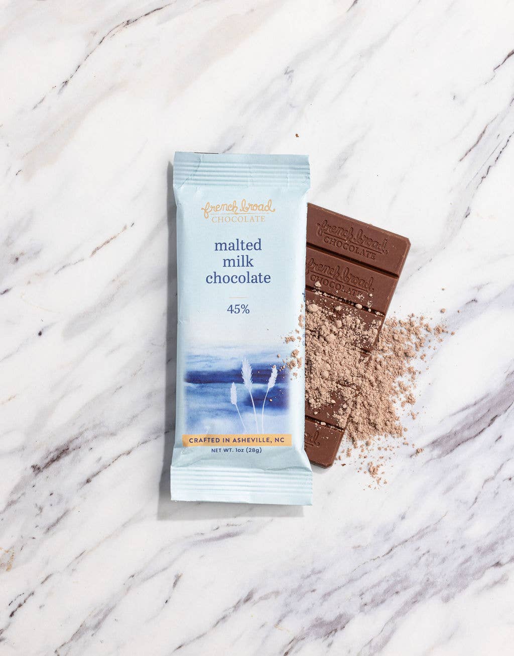 French Broad Chocolate 45% Malted Milk Chocolate bar and packaging on marble surface, crafted in Asheville NC, 1oz 28g