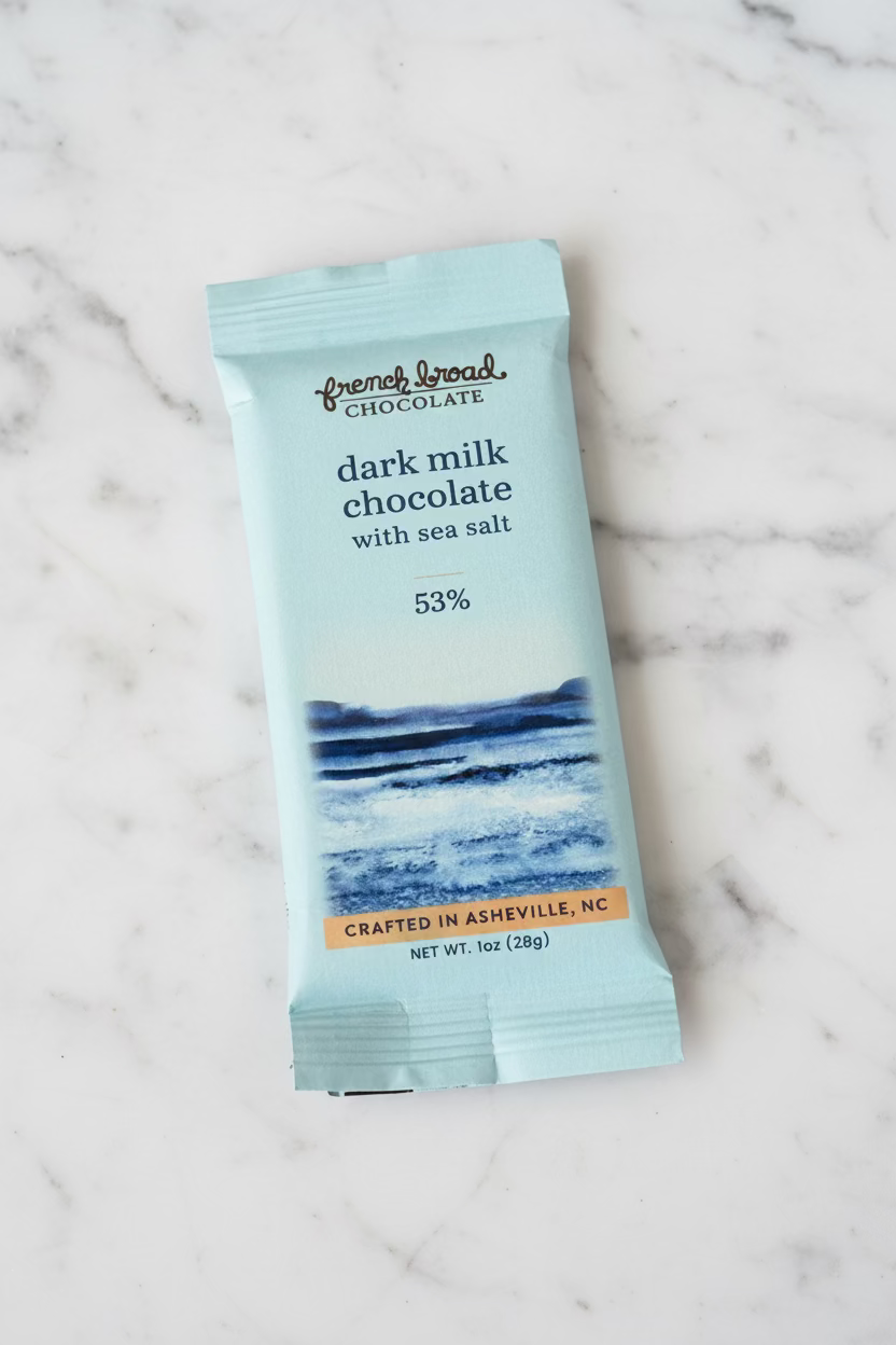 French Broad Chocolate 53% Dark Milk Chocolate with Sea Salt light blue wrapper on white marble surface, crafted in Asheville NC, 1oz 28g