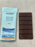 French Broad Chocolate 53% Dark Milk Chocolate Bar with Sea Salt unwrapped showing embossed segments next to light blue packaging