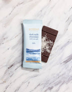 French Broad Chocolate 53% Dark Milk Sea Salt bar and packaging on marble surface, crafted in Asheville NC