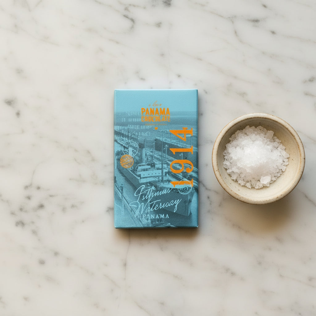 I Love Panama Chocolate 1914 dark chocolate bar beside a bowl of sea salt on white marble.