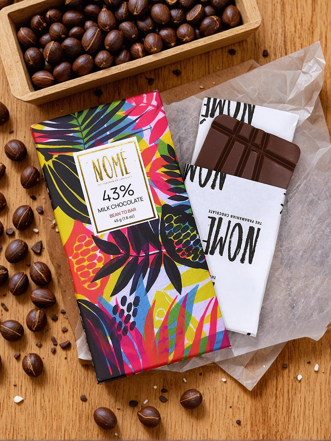 Colorful 43% chocolate bar packaging with 'NOME' branding on a wooden surface with cocoa beans.