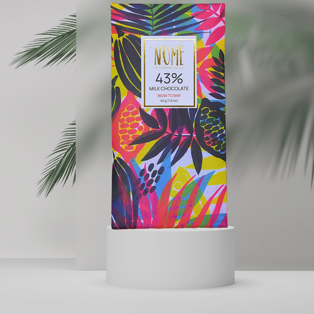 Nomé 43% Milk Chocolate bar packaging with vibrant tropical botanical print in pink, yellow, and green on white background, gold NOMÉ label, single-origin Panama, gluten-free, 45g