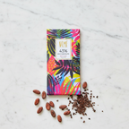 Nomé 43% Milk Chocolate bar with vibrant tropical botanical print packaging on white marble with raw cacao beans and nibs, single-origin Panama, gluten-free, bean-to-bar, 45g