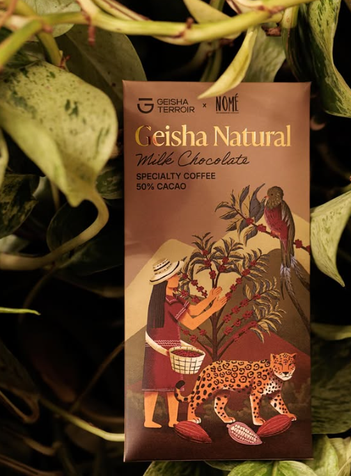 Nomé 50% Geisha Natural Milk Chocolate unwrapped bar with Geisha Terroir x Nomé packaging on leafy background, specialty coffee and single-origin Panama cacao