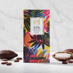 Nomé 63% Dark Chocolate bar packaging with vibrant tropical print on white marble background with cacao pods, single-origin Panama, vegan dairy-free