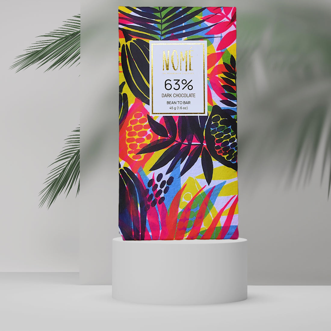 Nomé 63% Dark Chocolate bar packaging with vibrant tropical botanical print in pink, yellow, and green on white background, gold NOMÉ label, single-origin Panama, vegan, 45g