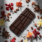 Nomé 63% Dark Chocolate bar on white marble with raw cacao beans, cacao nibs, and tropical flowers, single-origin Panama, vegan dairy-free