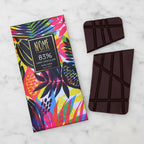 Nomé 83% Dark Chocolate bar unwrapped with vivid tropical print packaging on a marble surface, single-origin Panama, vegan dairy-free