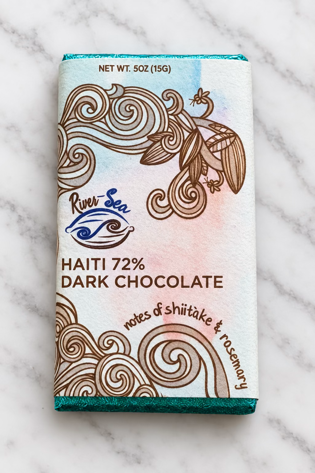 The 72% Haiti Dark Chocolate Bar packaging from River Sea Chocolates, on a white marble background, showing the tasting notes of shiitake mushrooms and rosemary.