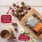 Cacao paste packaging with chocolate discs and a mug on a wooden surface