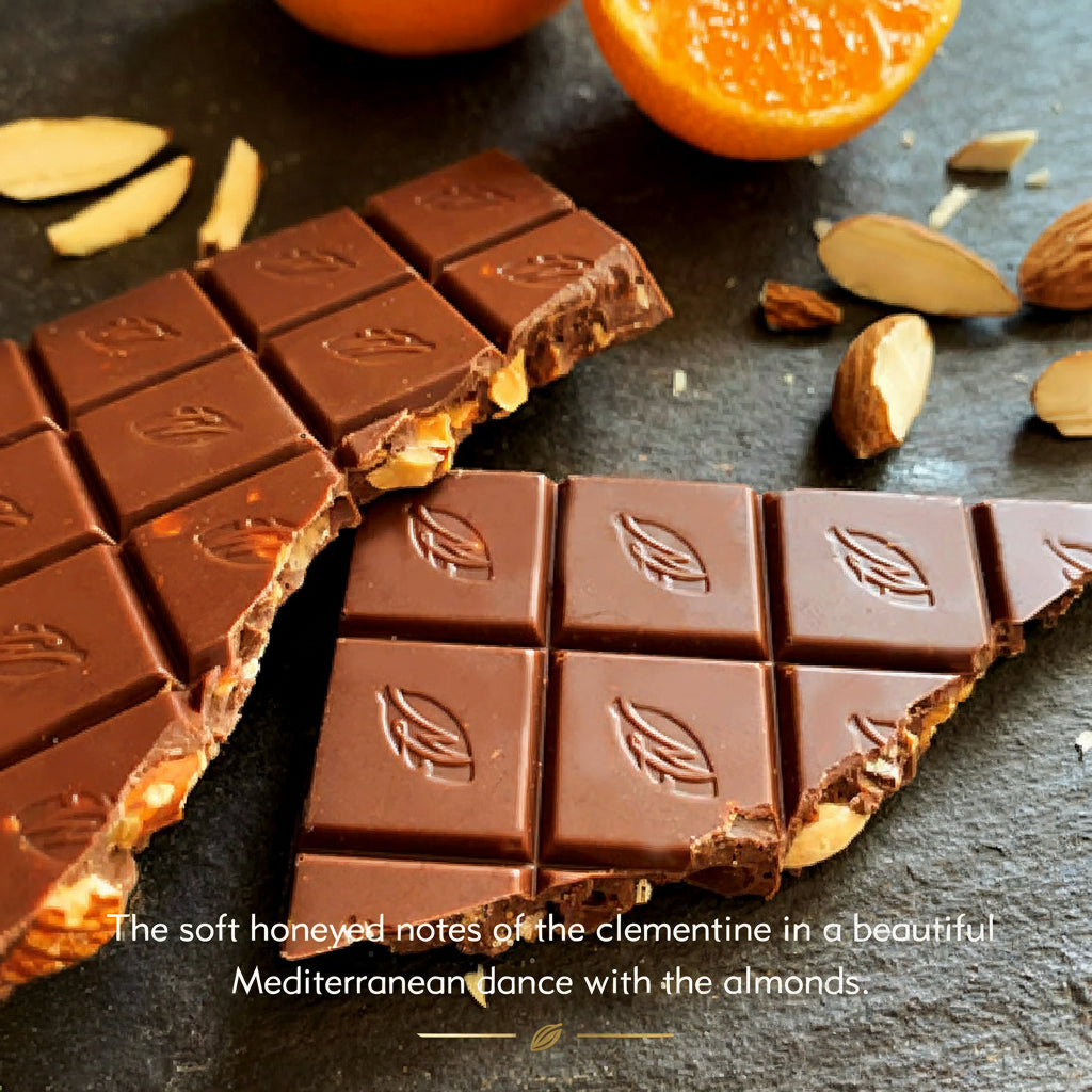 Willie's Cacao 44% Milk Chocolate bar with Clementine and Almonds broken open on dark slate with fresh clementine halves and whole almonds, soft honeyed notes in a Mediterranean dance