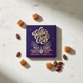 Willie's Cacao Milk of the Stars 54% Indonesian Surabaya Milk Chocolate deep purple box on white marble with soft caramel pieces and raw cacao beans, SOFI Award winner, single-origin Indonesia, 50g