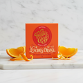 Willie's Cacao Luscious Orange 65% Dark Chocolate orange box on white marble with fresh orange slices, delicate orange dark chocolate, natural bean-to-bar, single-origin, 50g