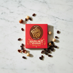 Willie's Cacao 70% Dark Chocolate Hazelnut Raisin red box on white marble surface with whole hazelnuts and raisins, smooth simple and moreish, natural bean-to-bar, 50g
