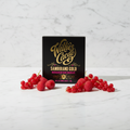 Willie's Cacao 71% Sambirano Gold Madagascan Dark Chocolate bar in black and gold packaging standing upright on white marble, styled with fresh raspberries and red currants
