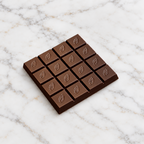 Unwrapped Willie's 100% Pure Gold  cacao bar with embossed cacao-pod squares on marble.