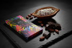 Nomé 83% Dark Chocolate bar with tropical print packaging on dark surface with chocolate pieces and cacao pod, single-origin Panama
