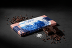 Nomé 93% Chocolate Oscuro bar with Sea Salt and Cacao Nibs packaging with cacao pods on warm neutral surface with tropical leaves, single-origin Panama, vegan