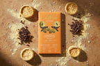 Cacao Adventures Unmilk'd Chocolate 53% bar surrounded by lucuma fruit, raw cacao nibs, and flaky sea salt on a warm earthy surface